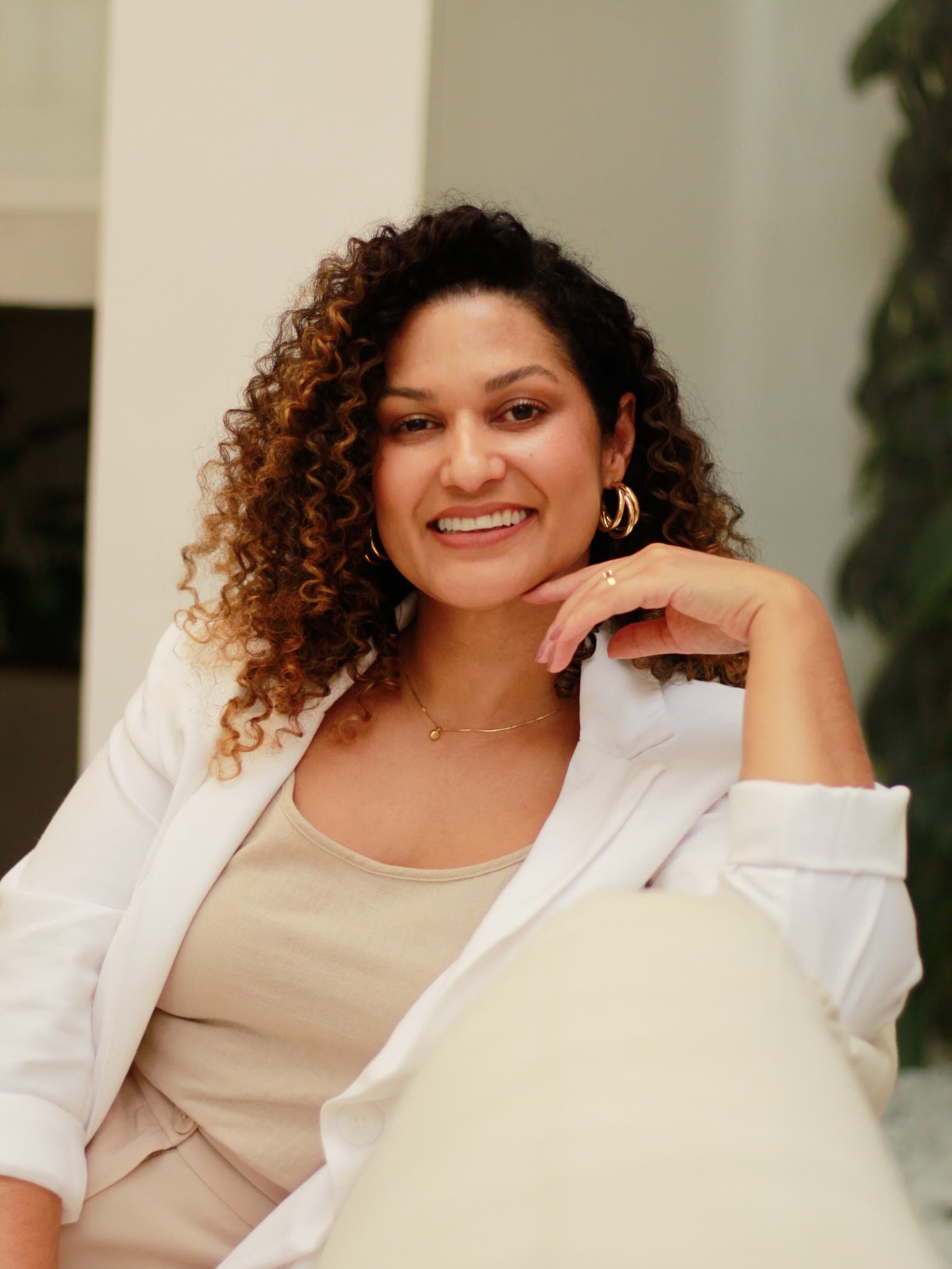 Karla França, psicóloga clínica, sorrindo sentada em um sofá